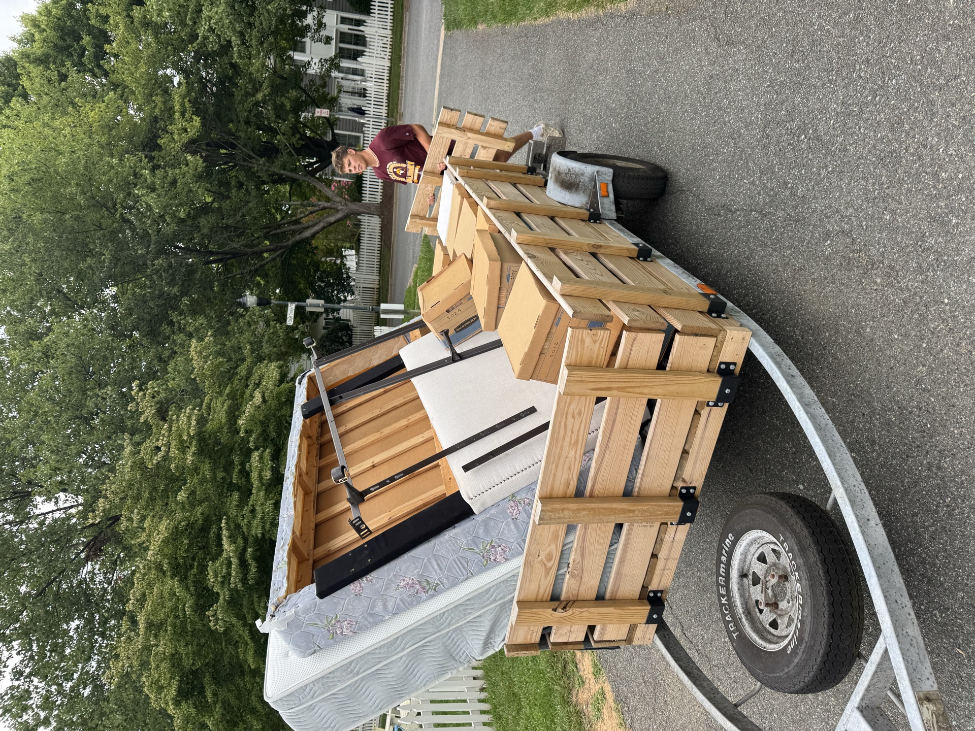 Trailer loaded with a mattress and boxes on a suburban street