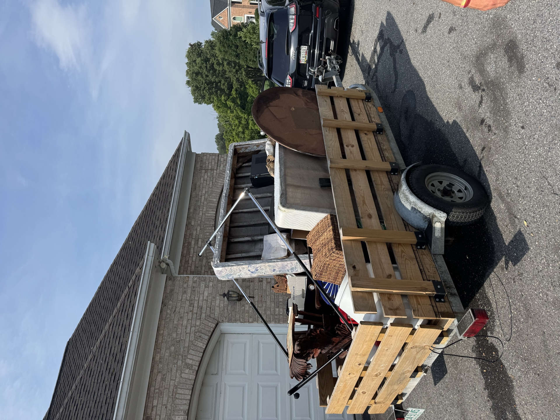 Trailer loaded with a mattress and lawn equipment for a garage cleanout
