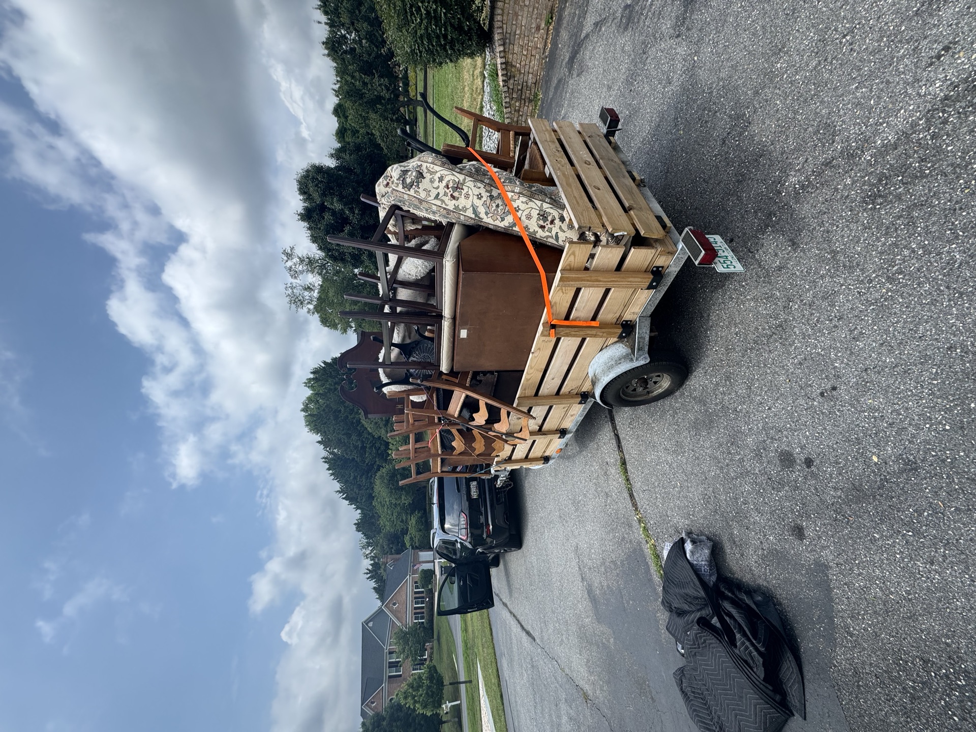 Trailer loaded with a hutch and wood chairs for furniture removal