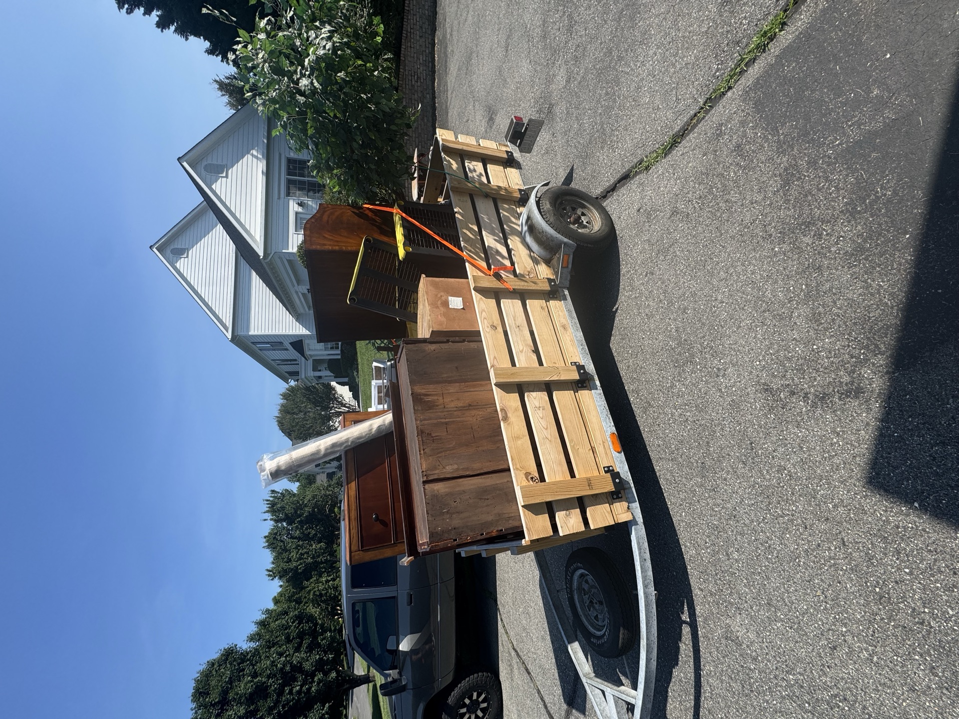 Trailer loaded with wood furniture and a storage chest for haul away
